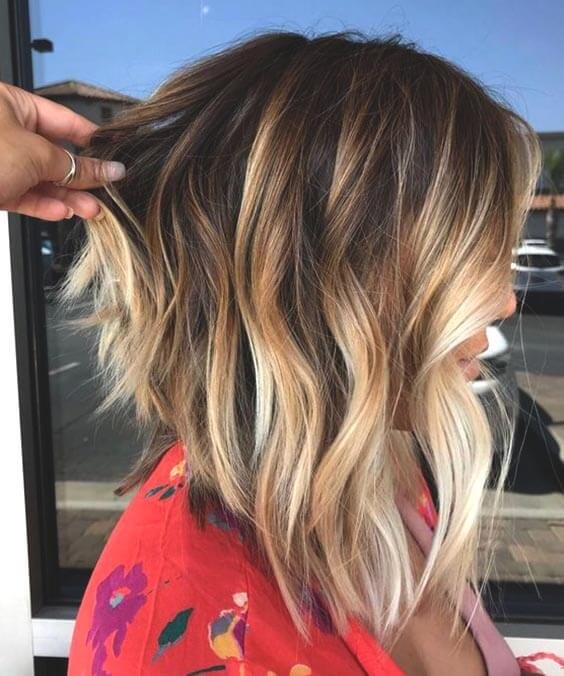 A chic choppy bob hairstyle with textured and uneven ends, complemented by an ombre color effect that adds depth and dimension to the hair